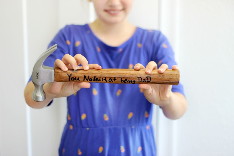 child holding diy personalized hammer that says "You Nailed it at being Dad"