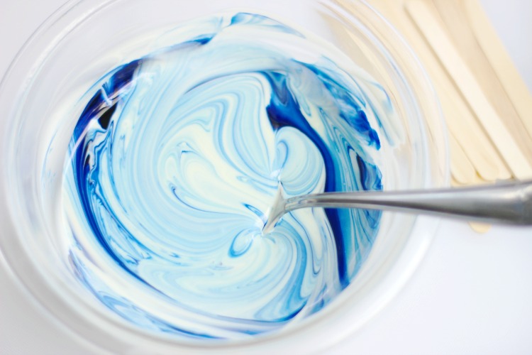 stirring blue coloring into white chocolate for shark rice krispies treats