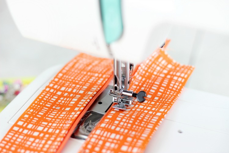 sewing machine stitching fabric to zipper