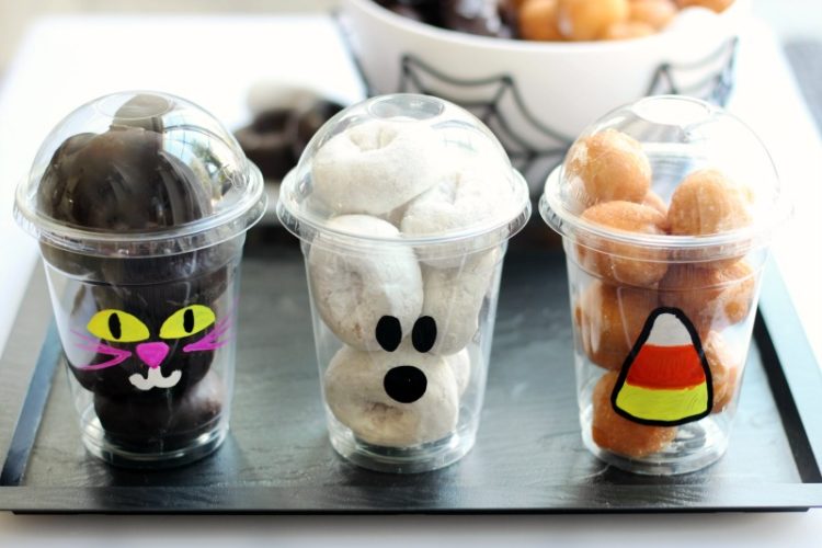 3 plastic cups painted with halloween designs and filled with donut holes