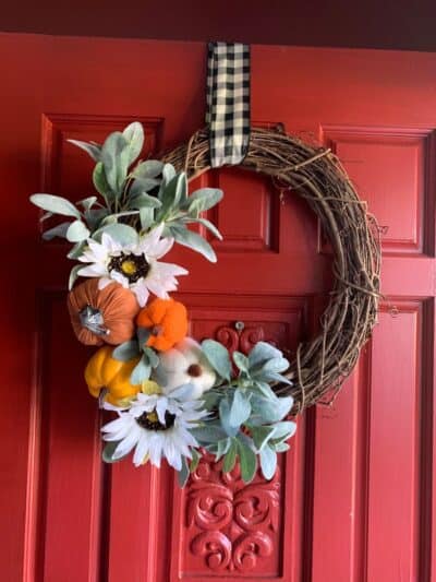 Fall pumpkin wreath hanging on red door.