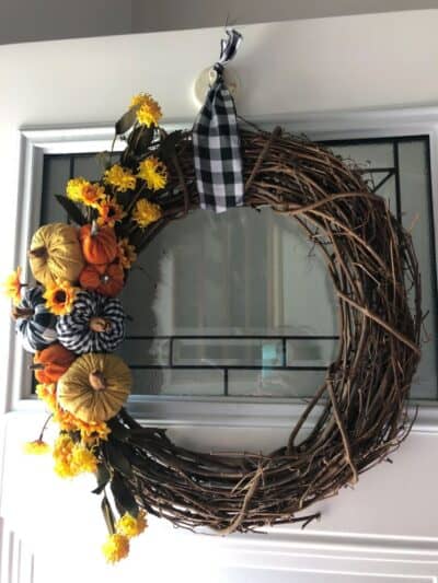 Pumpkin wreath with sunflowers on white door.