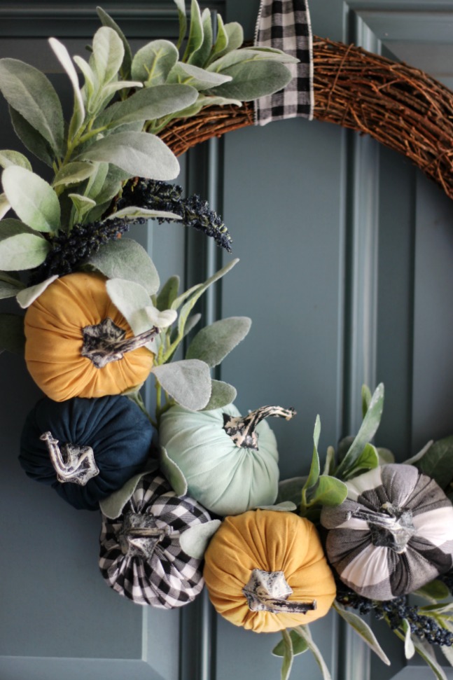 pumpkin wreath with buffalo check ribbon hanging on door