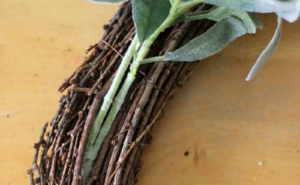 Greenery stems tucked into crevices on grapevine wreath base.