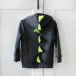 Grey dinosaur hoodie hanging on a hanger.