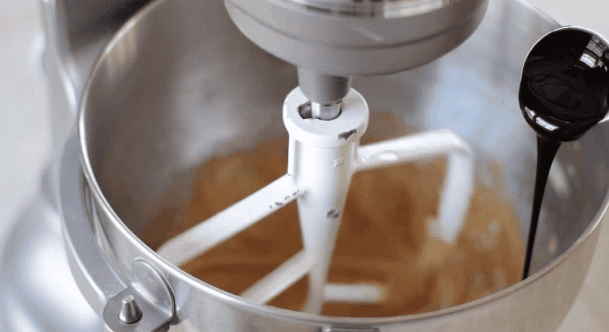 Molasses being poured into stand mixer bowl.