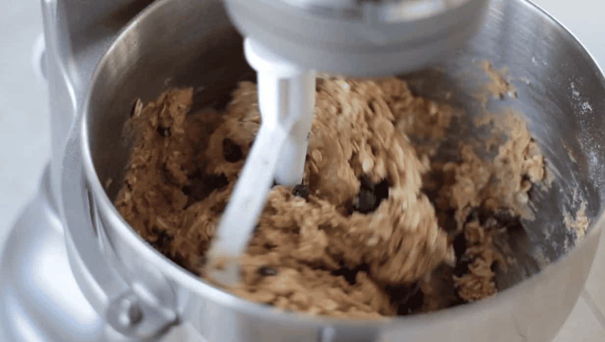 Stand mixer metal mixing bowl of oatmeal cookie dough.