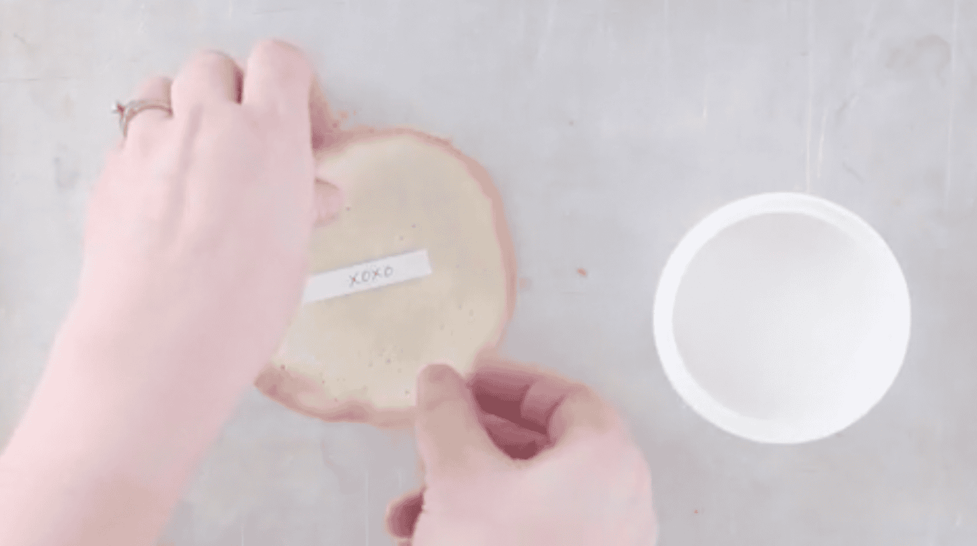 Hands adding fortune to cookie before shaping fortune cookie.