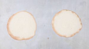 2 baked fortune cookies flat on baking sheet