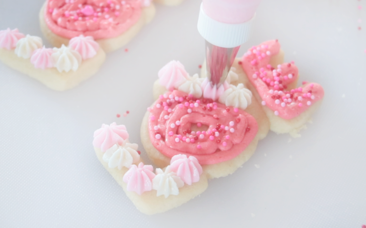 decorating love shaped cookie with star bursts of frosting