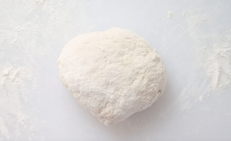 ball of pizza dough on floured surface