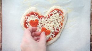 adding pepperoni to heart pizza