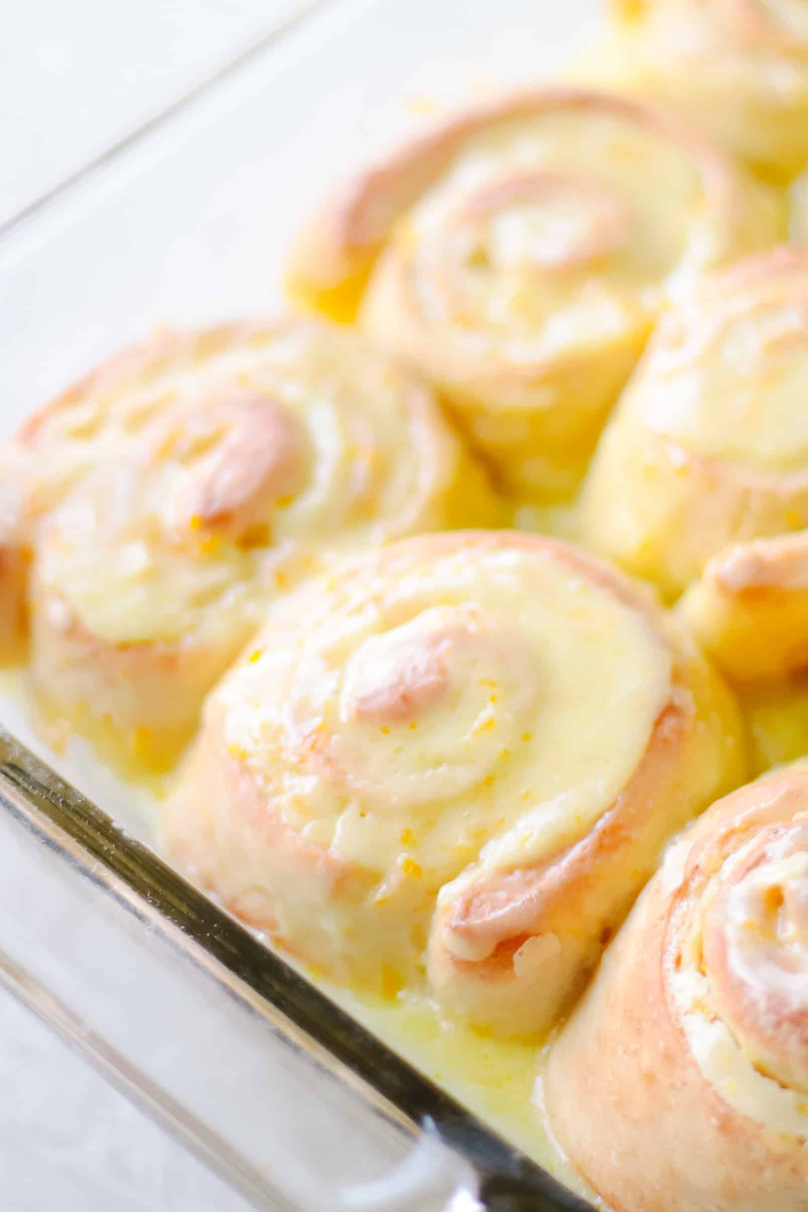 Glass baking dish with baked orange rolls.