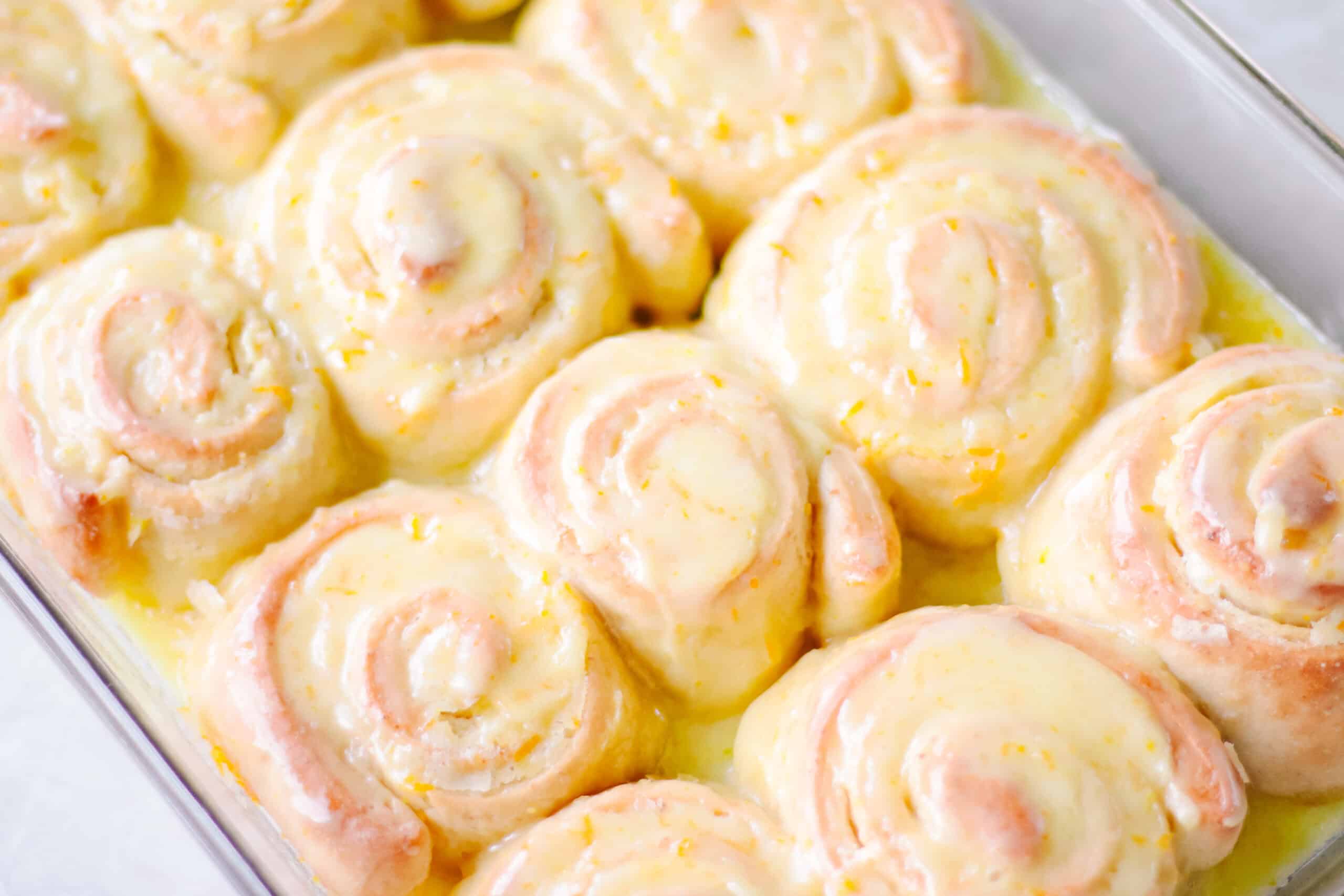 Glass baking dish with orange sweet rolls.