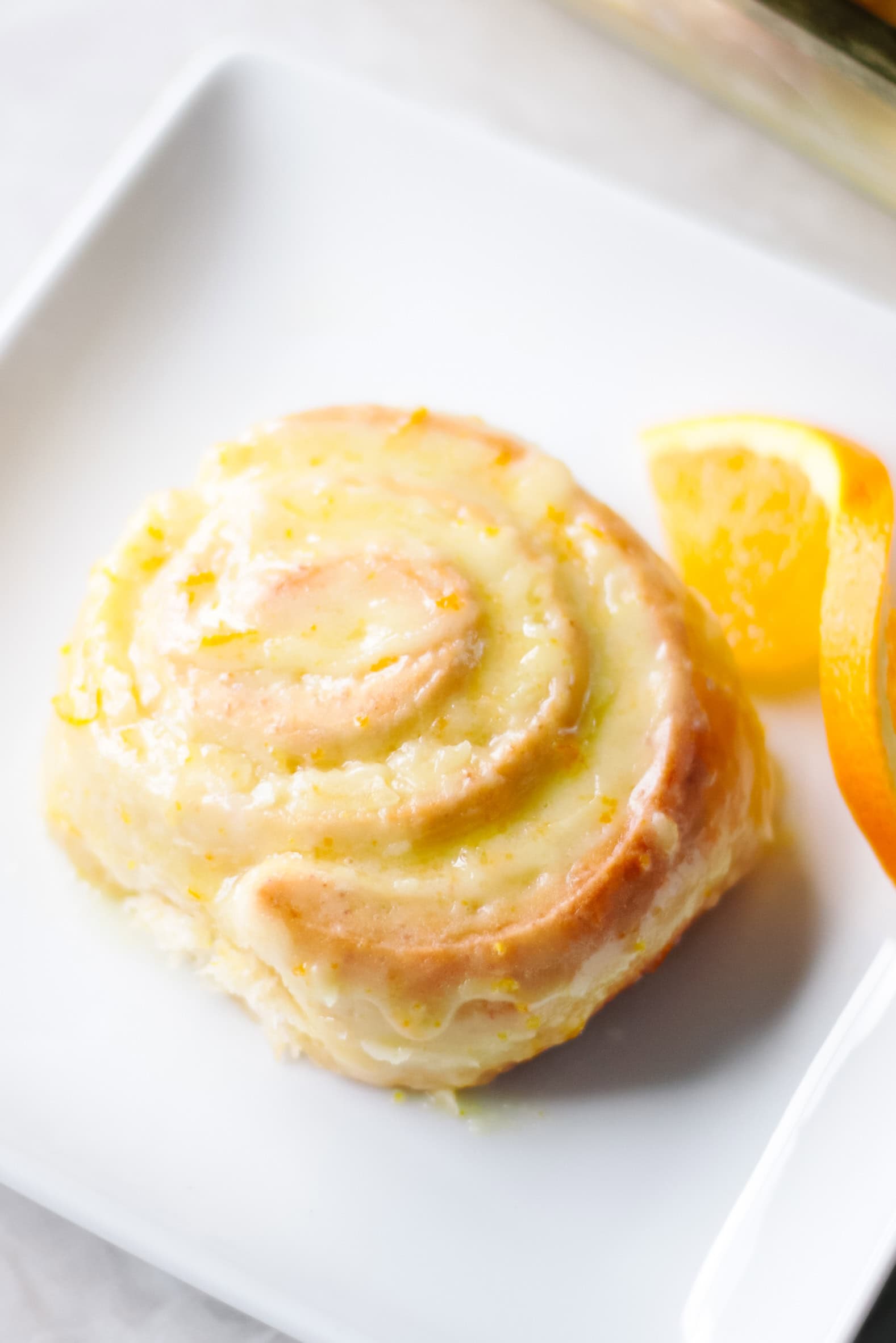 White plate with an orange sweet roll.