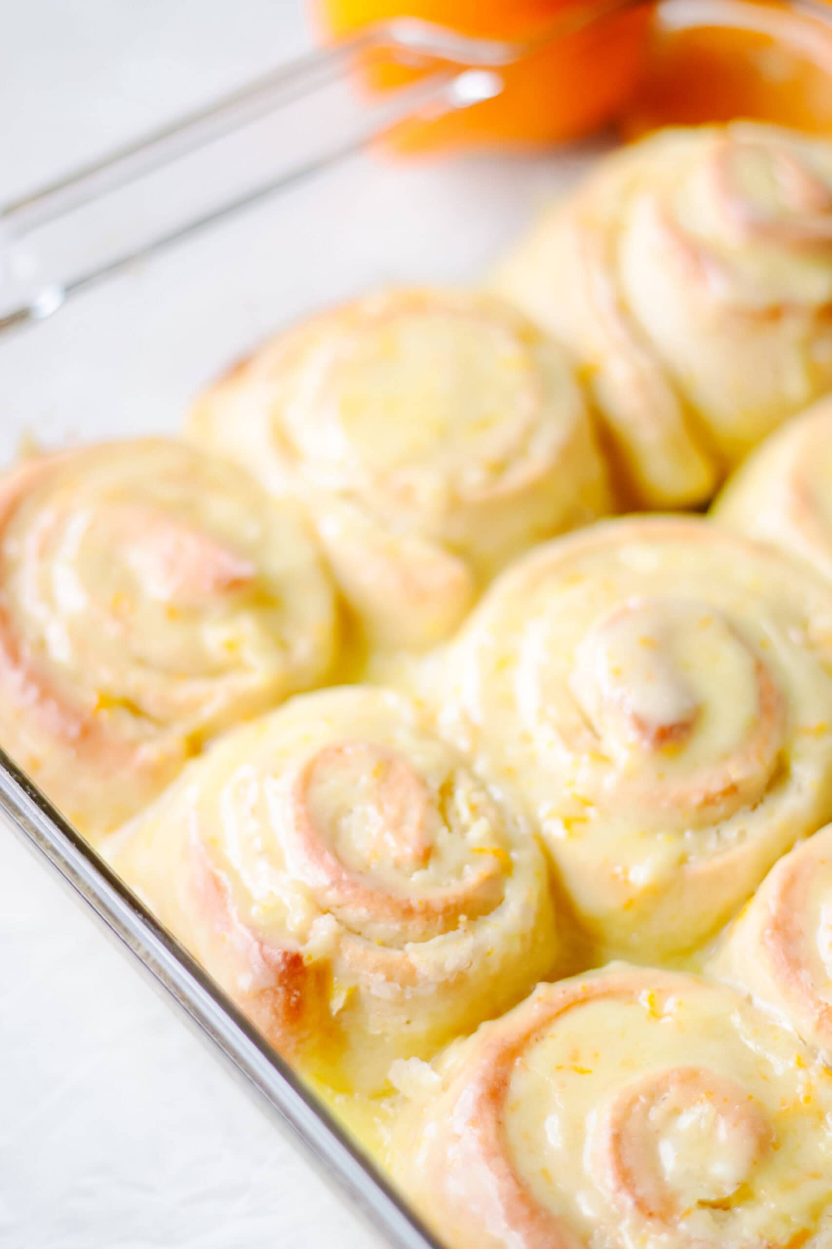 Baking dish of baked and glazed orange rolls.
