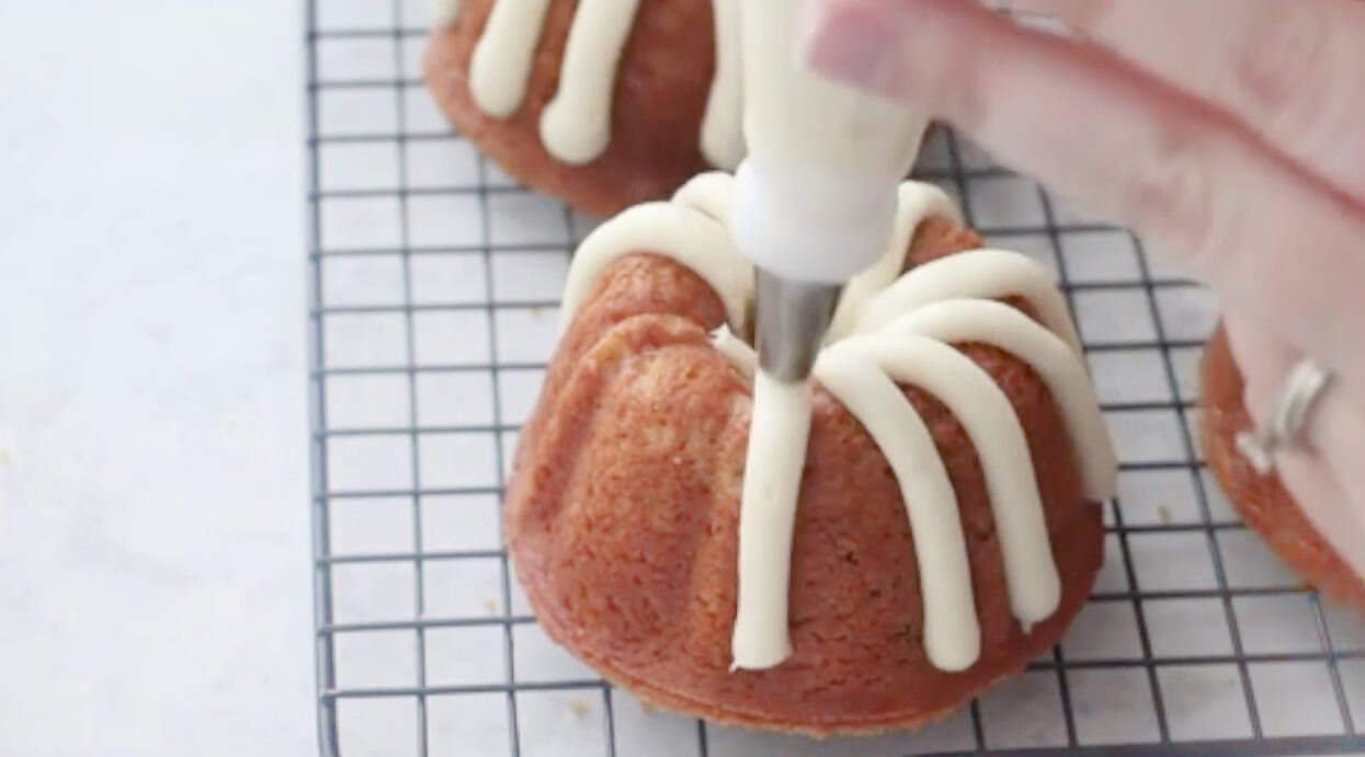 Cream cheese frosting piped onto mini bundt cakes.