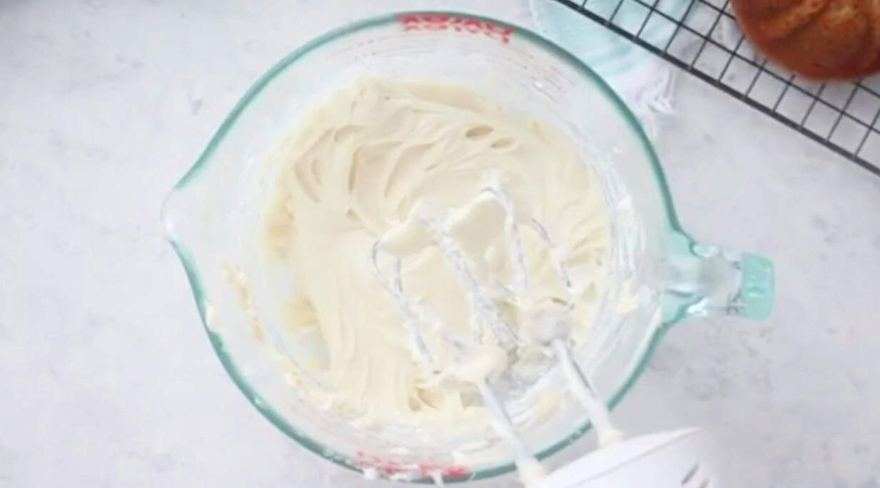 Glass mixing bowl of cream cheese frosting.
