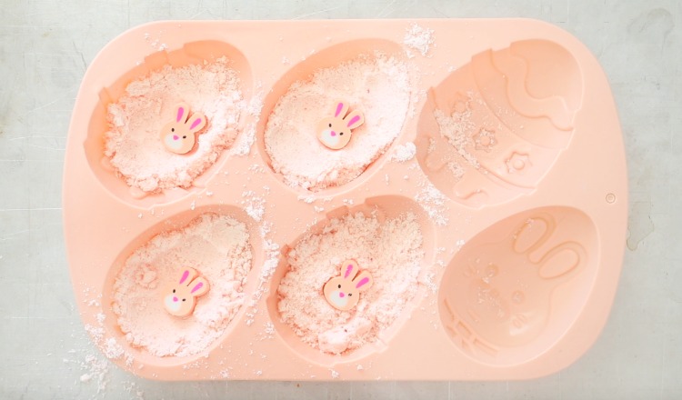 soap mold with bath bomb mixture and bunny toy in each bath bomb cavity
