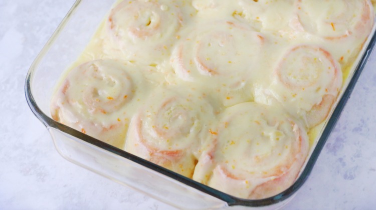 orange rolls with frosting in baking dish