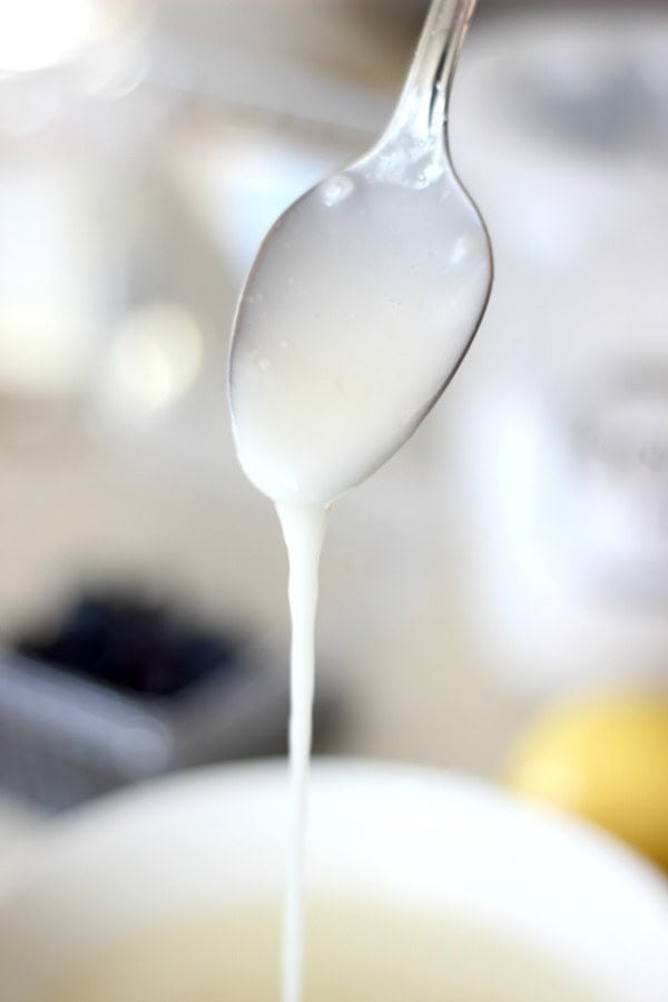 Metal spoon with icing dripping off.