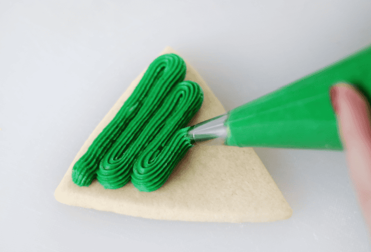 triangle sugar cookie with green frosting and frosting tip