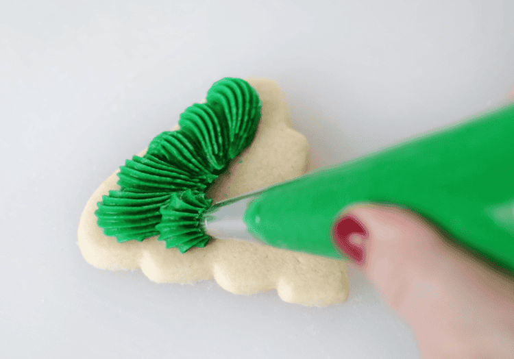bag of green frosting piped onto tree sugar cookie