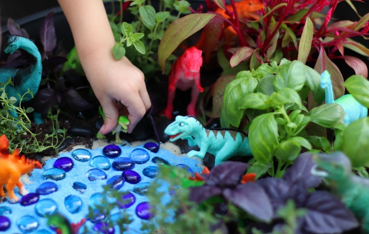 child's hand playing with dinosaur in garden