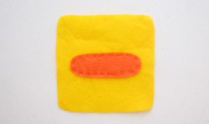 yellow square of felt with duck beak stitched on