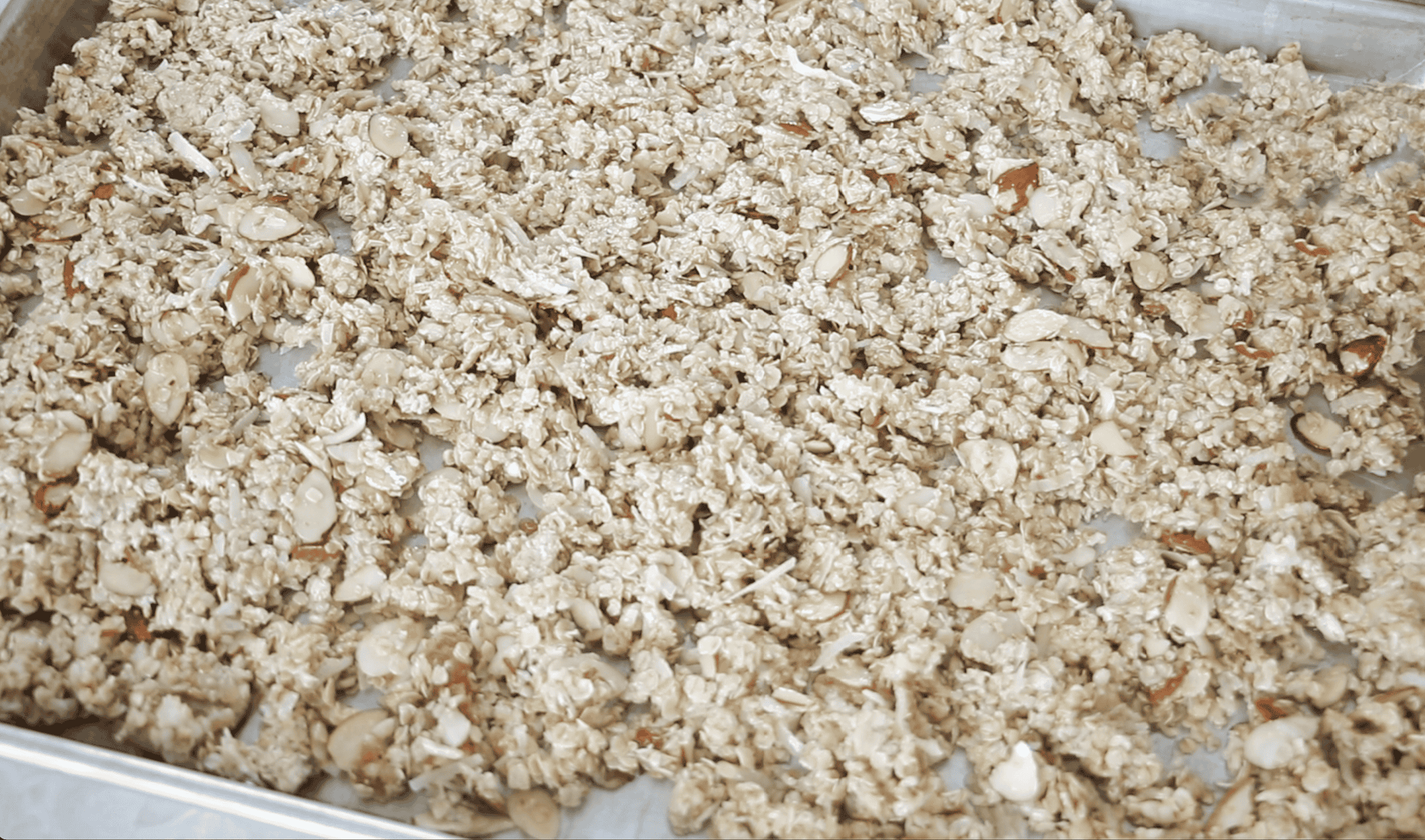 Unbaked granola mixture on large baking sheet.