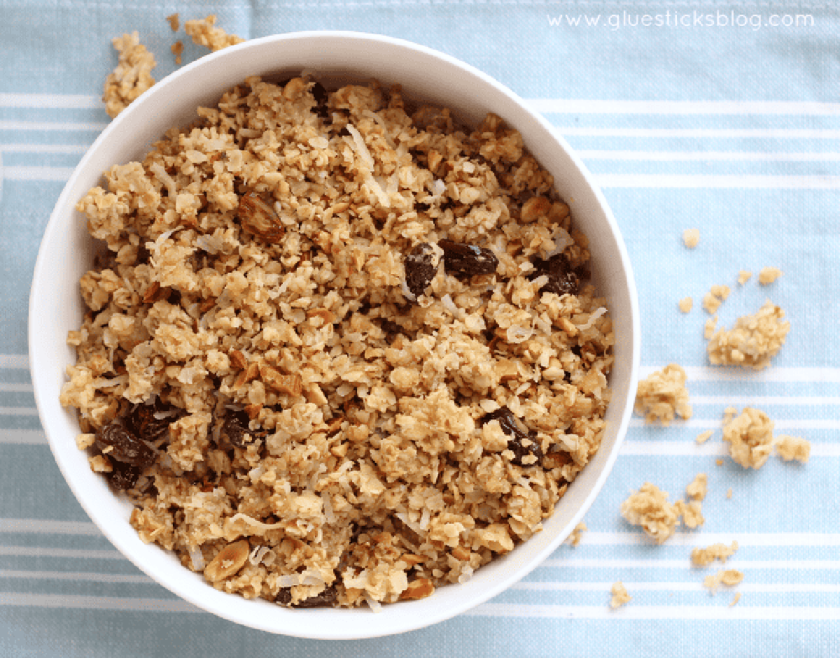 White bowl of granola with raisins on a blue placemat.