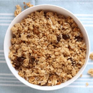 white bowl of granola with raisins on a blue placemat.