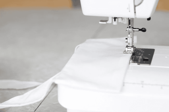 Sewing maching sewing white fabric.