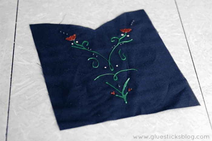 Navy blue fabric with fabric paint floral designs painted on front.