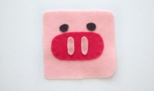 pig softie face glued onto pink felt square