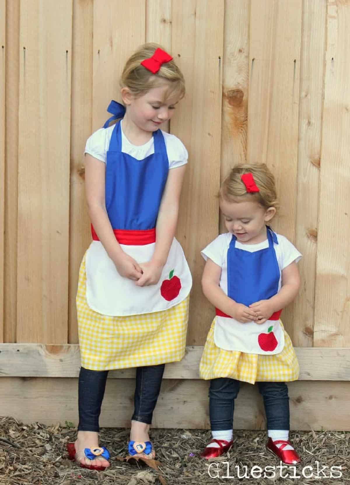 Two little girls wearing Snow White aprons.