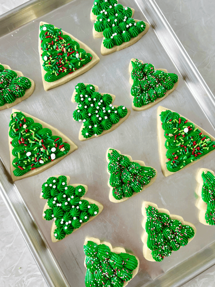 Baking sheet of green christmas tree sugar cookies.