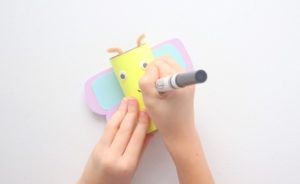 child drawing a mouth on butterfly craft