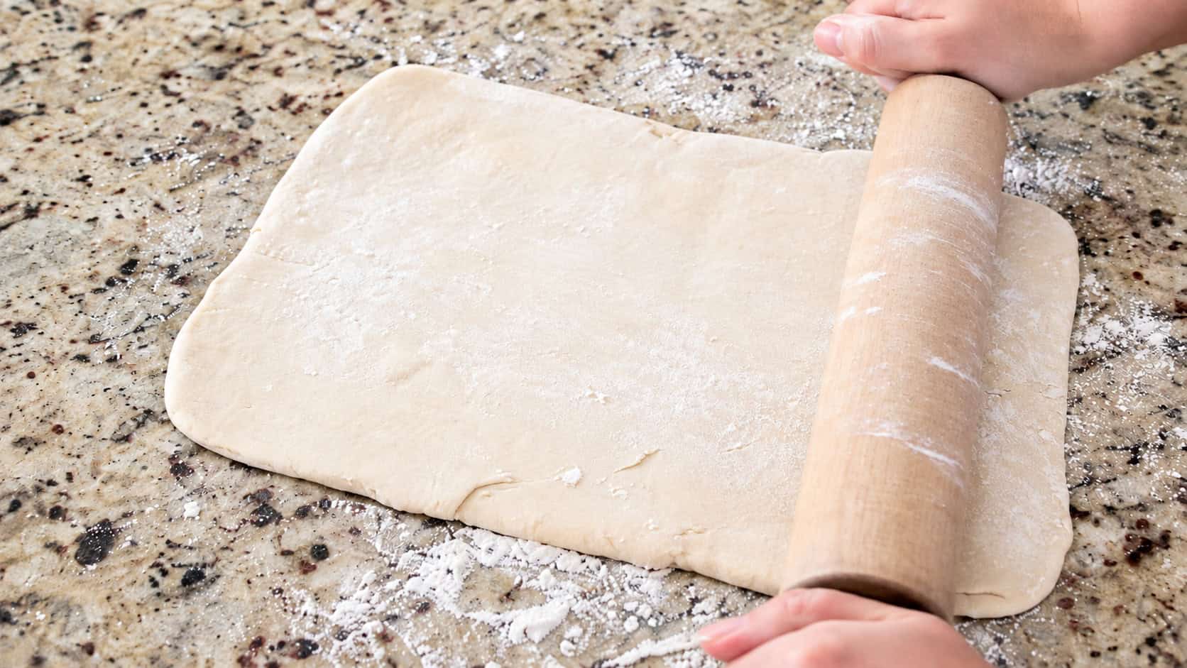 Puff pastry dough rolled out with rolling pin.