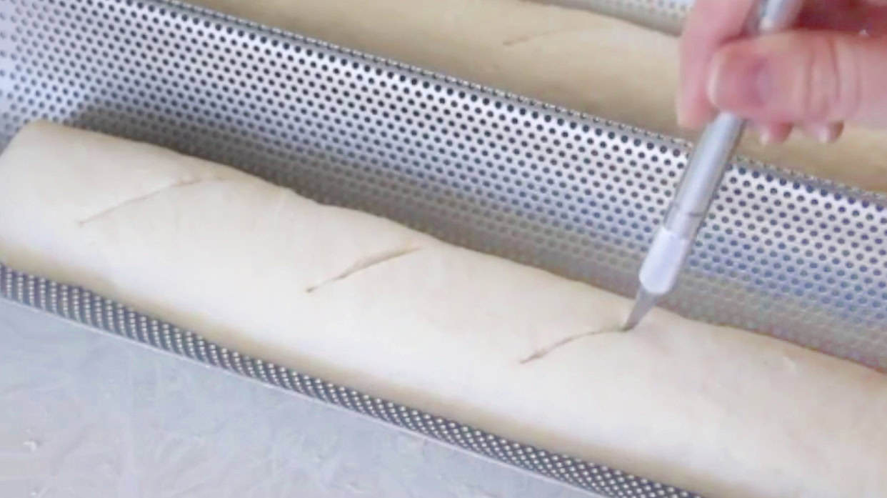 Bread loaves scored in metal baguette pan.