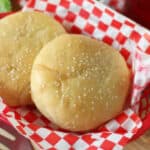 Two hanburger buns in fry basket with checkered red and white liner.