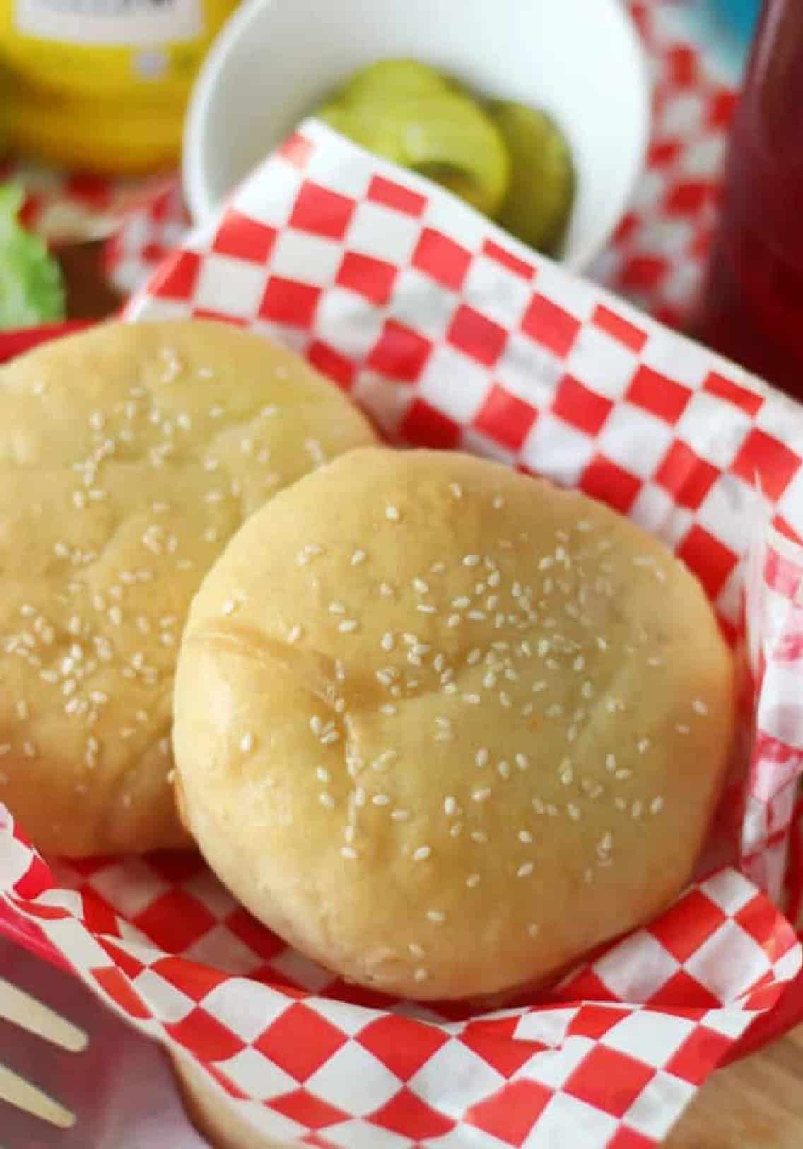 Two hanburger buns in fry basket with checkered red and white liner.