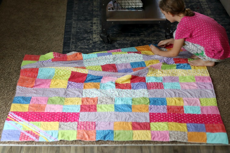 girl cutting off loose threads from quilt