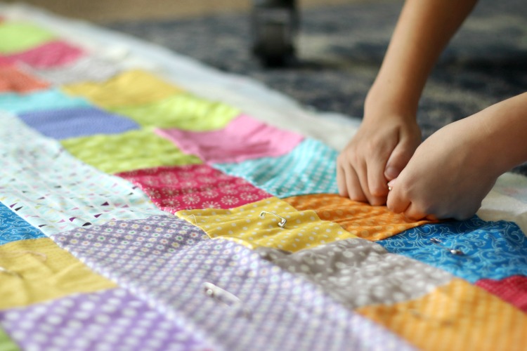 hands pinning safety pins to quilt top