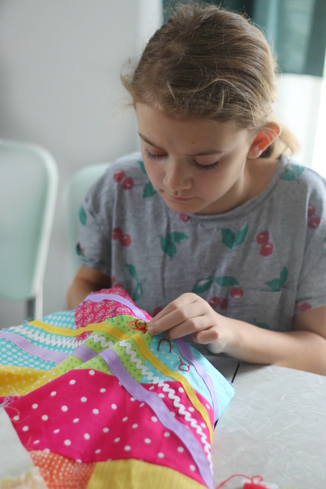 girl embroidering name onto quilt top