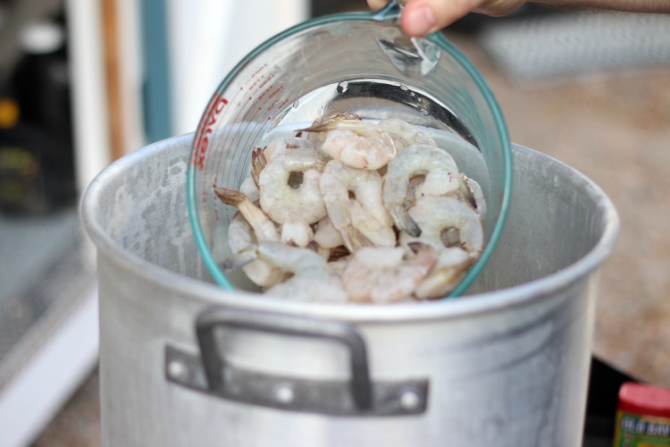 uncooked shrimp in glass bowl being poured into large pot