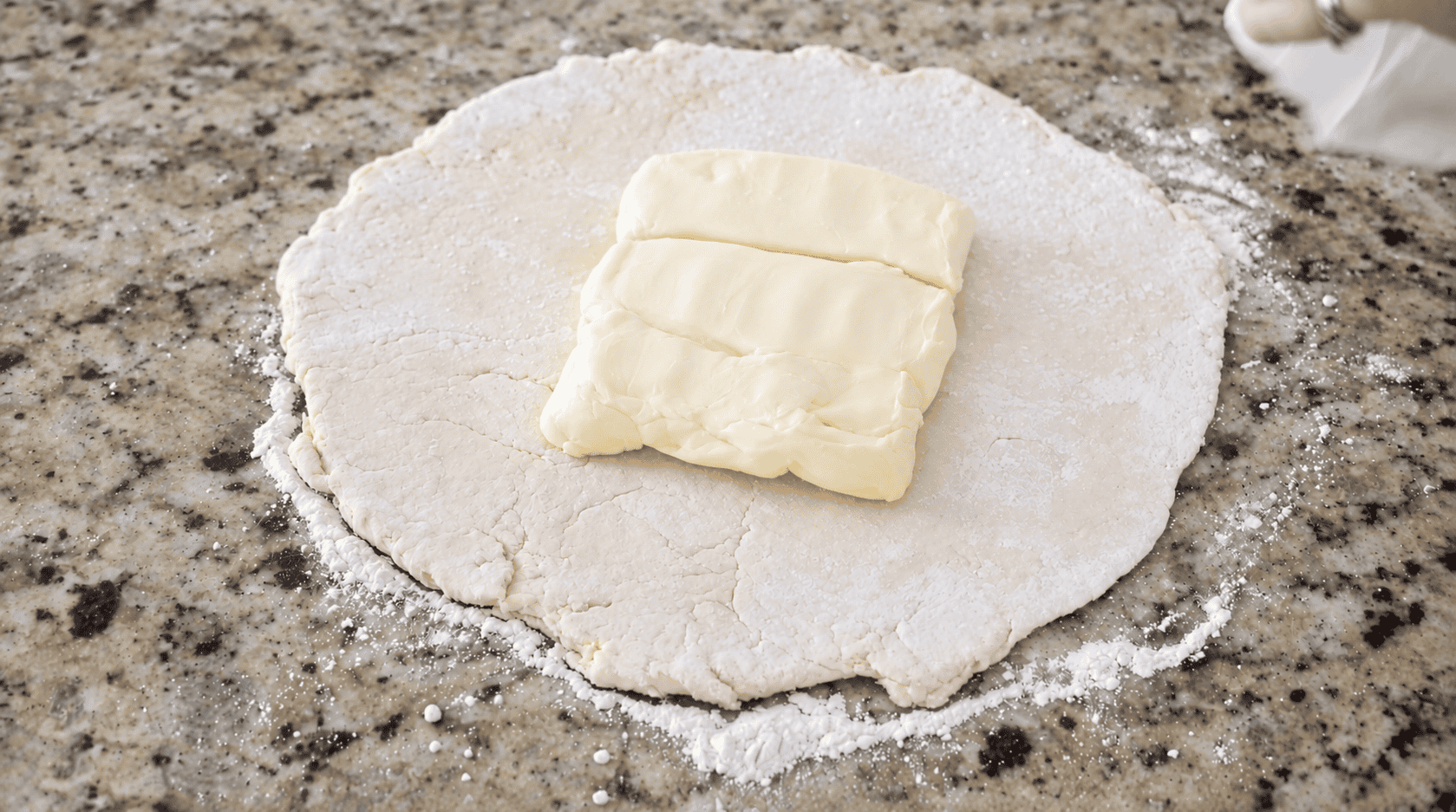 Dough rolled out into a circle with square of butter on top.