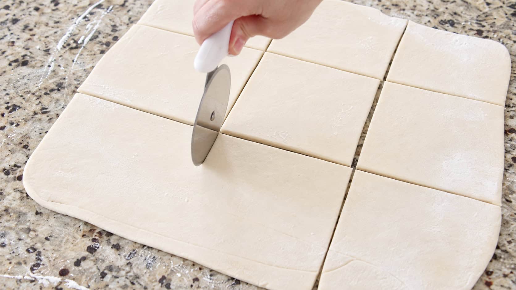 Puff pastry dough rolled out and sliced into squares using a pizza cutter.