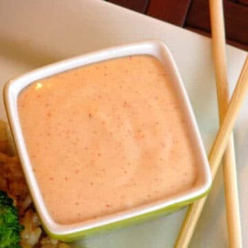 Square bowl of yum yum sauce on plate with chop sticks.