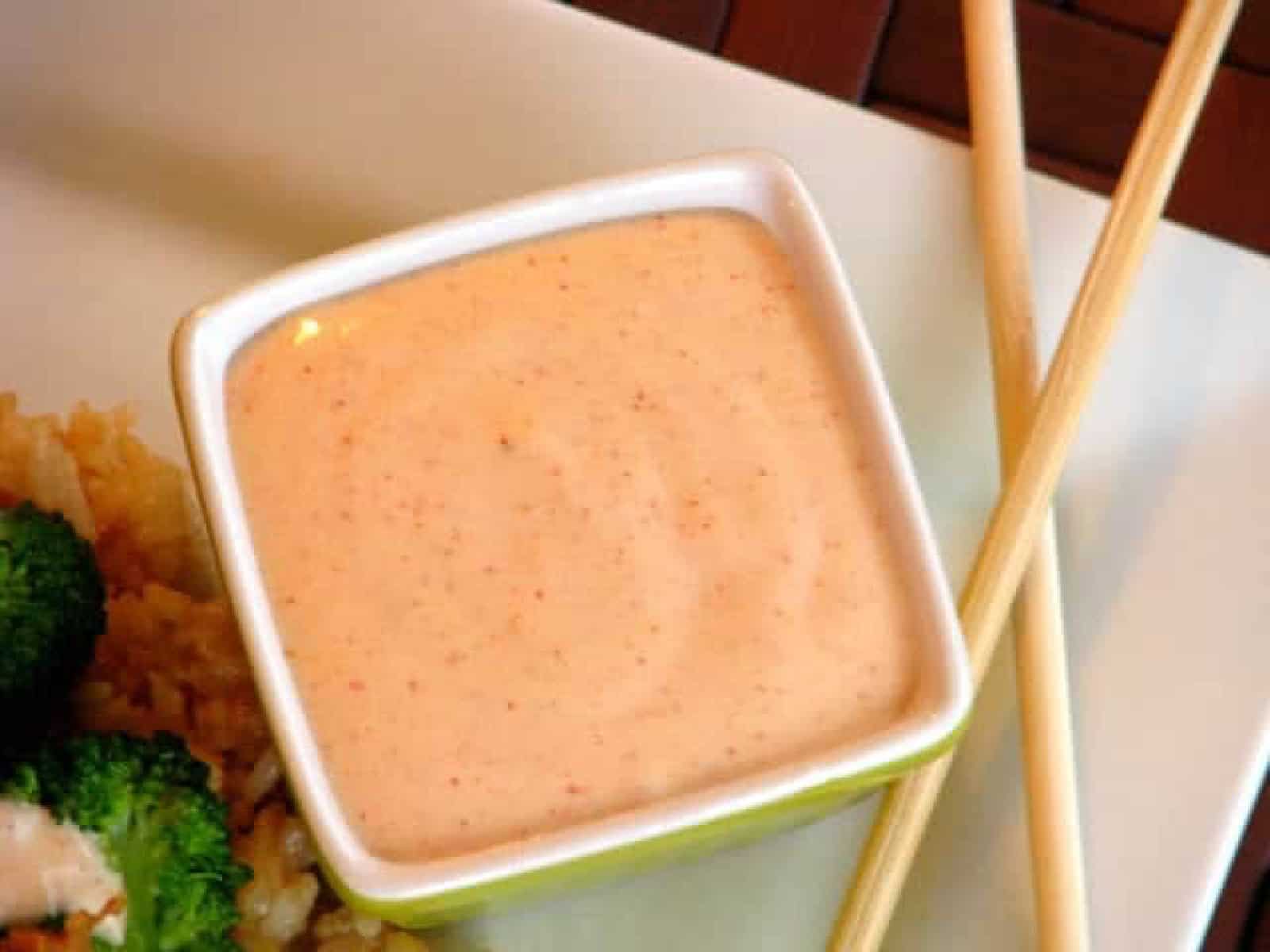 Square bowl of yum yum sauce on plate with chop sticks.